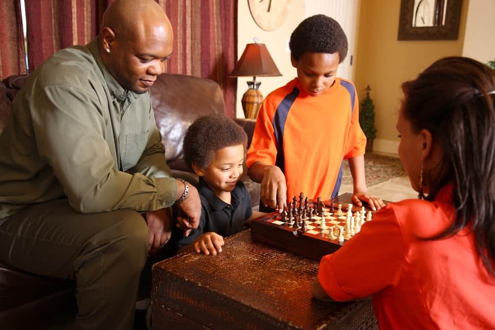 Family in living room playing chess together