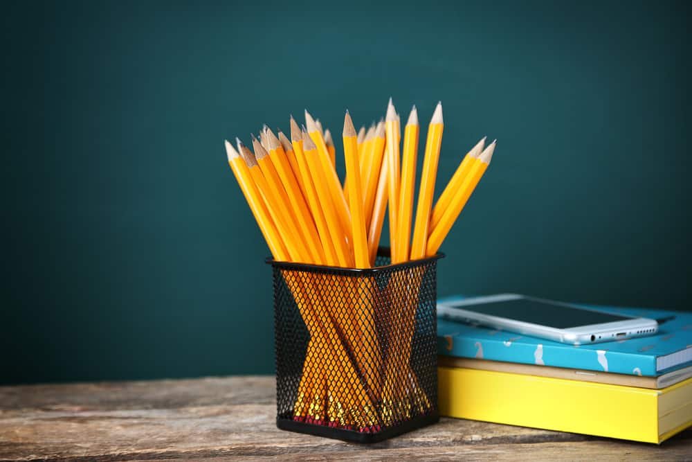 Many pencils in the metal holder on wooden table sudoku