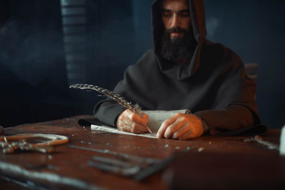 Medieval monk sitting at table and write dominoes