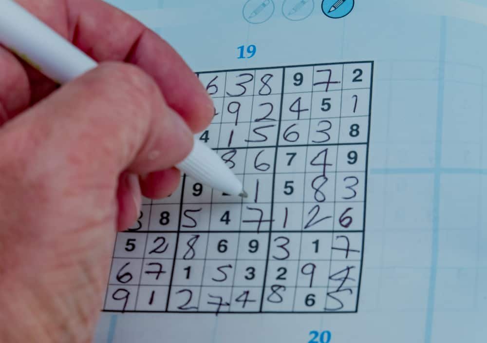 male’s hand completing a sudoku puzzle