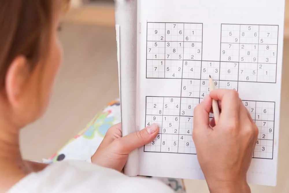woman doing crosswords in room sudoku