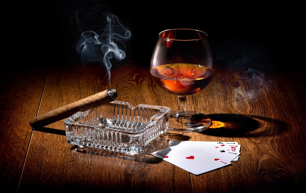 Playing cards near wineglass of whiskey and cigar poker