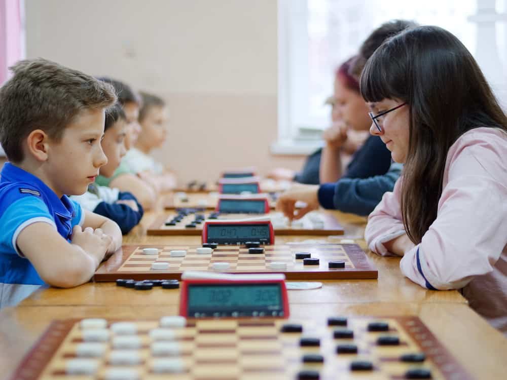 children and adults play checkers