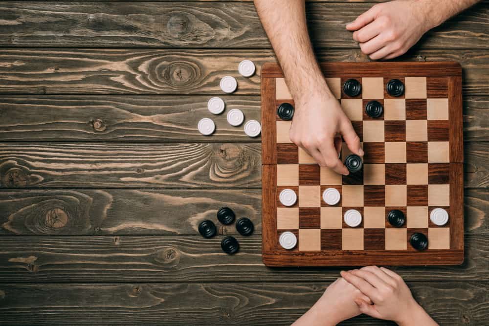 couple playing checkers on wooden background