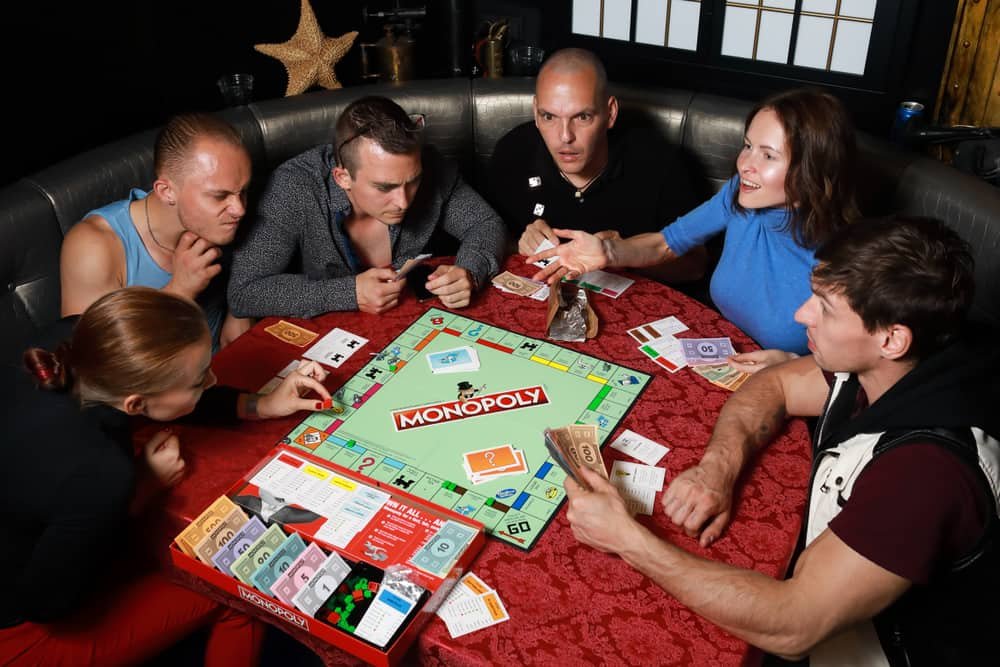Group of people playing Monopoly board game together at night
