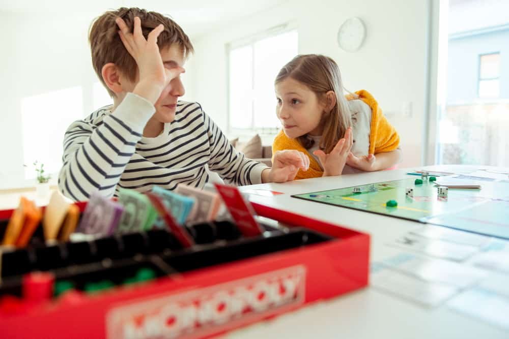 Happy children having fun playing the board game, monopoly
