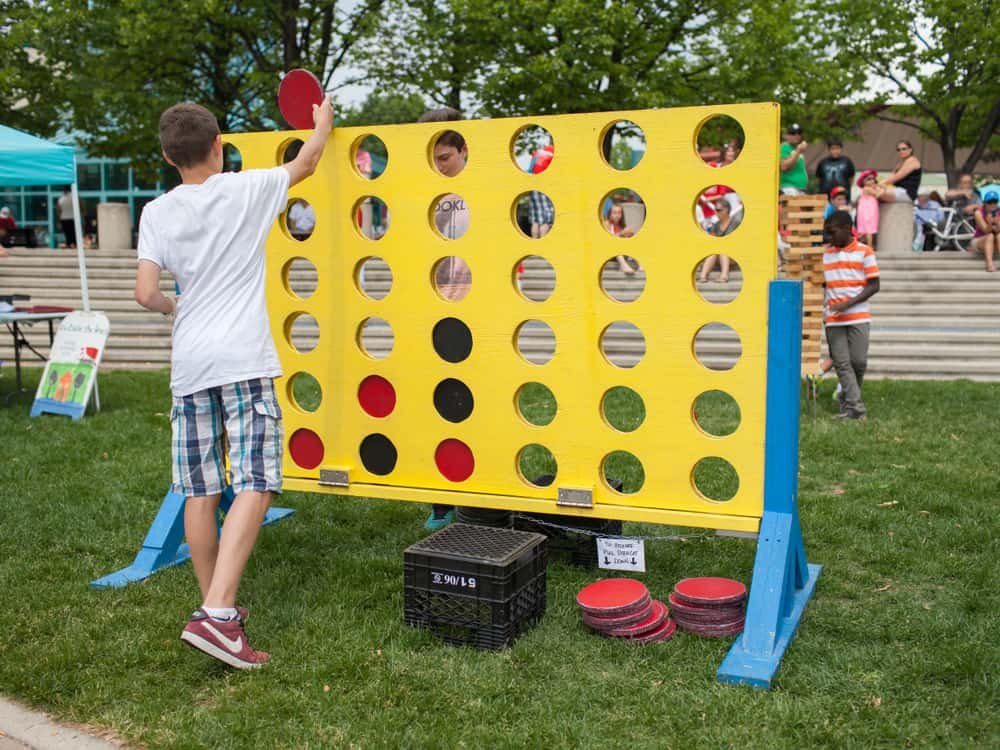 Two boys playing a giant-sized version of Connect Four outdoors