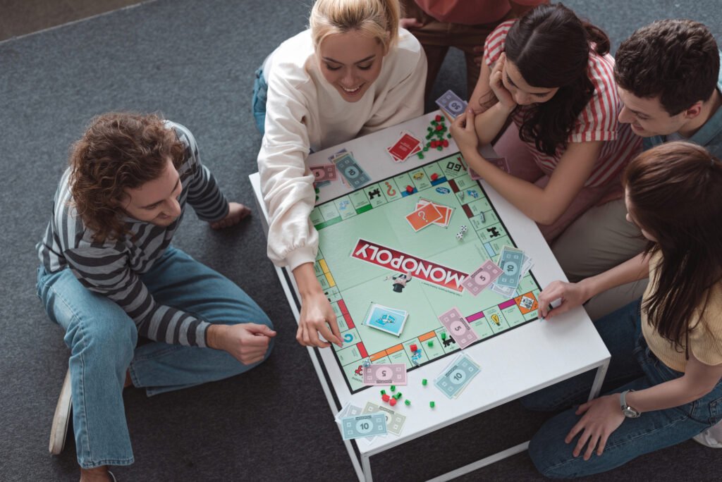 friends sitting on floor and playing monopoly game