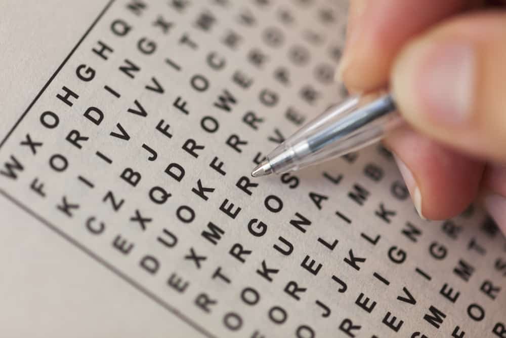 Woman's hand with ballpoint pen and wordsearch puzzle