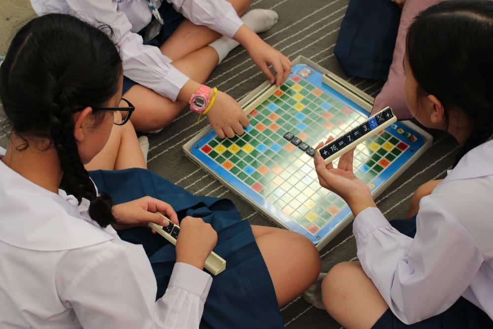 School Girls Play a Math Scrabble Style Board Game on the Floor