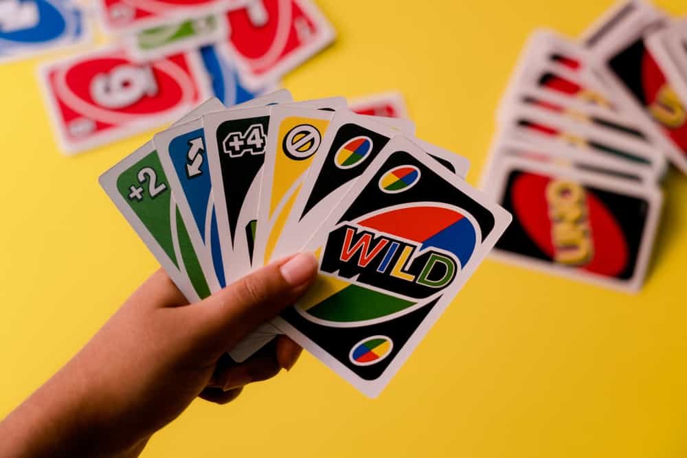 Uno special cards held against a deck of cards on a yellow background