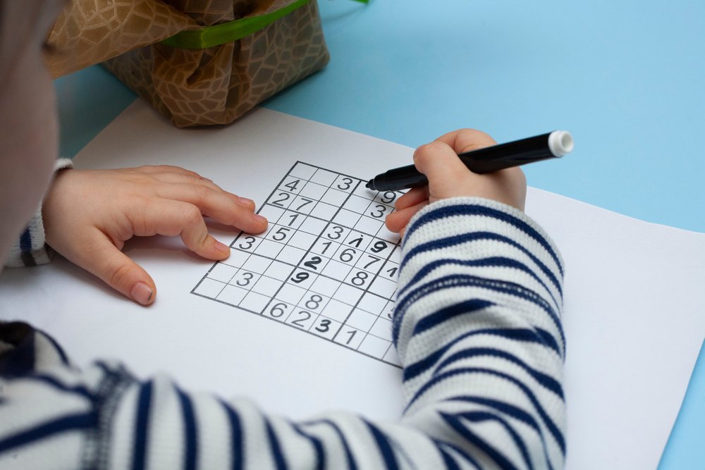 Child solves Japanese crossword sudoku