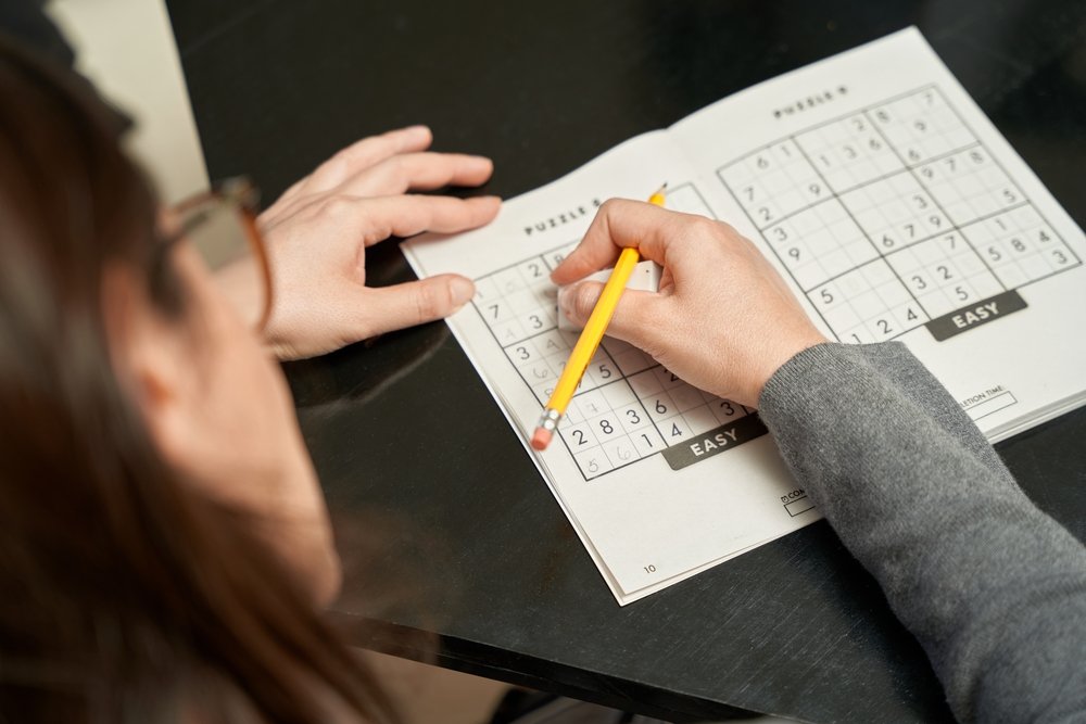 Woman playing sudoku game at home