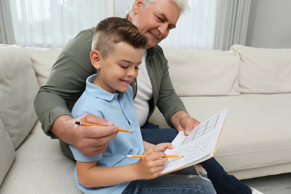 boy with his grandfather solving sudoku puzzle