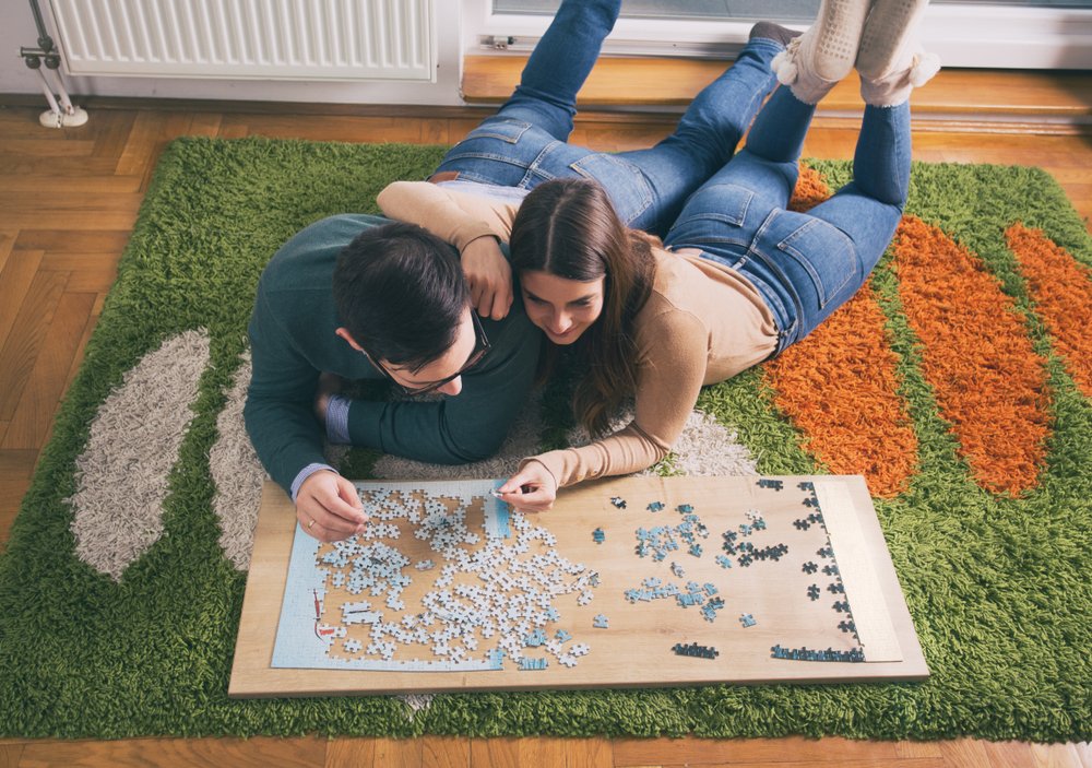 couple laying on floor and doing puzzle