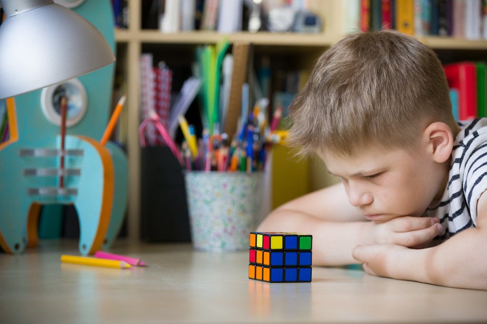 sad kid boy watching at Rubik's cube