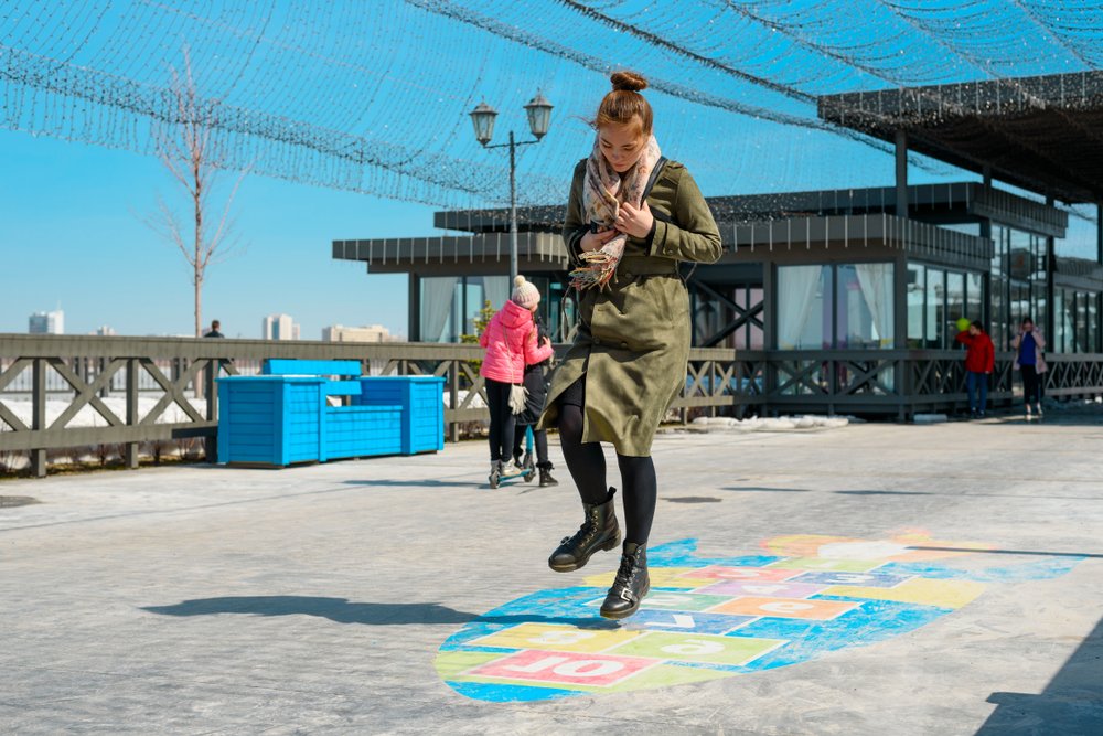 woman in a green coat jumping