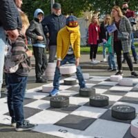 Children play checkers on a large playing field