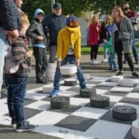 Children play checkers on a large playing field