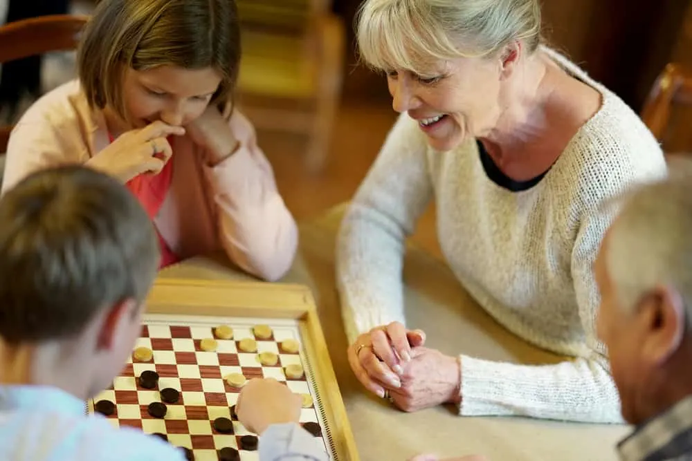 Grand-parents with grandkids playing checkers