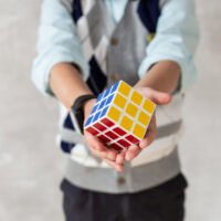 Close-up of Rubik's cube in hands of young boy in casual clothing
