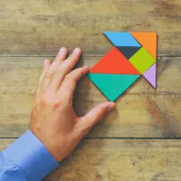 man's hand pointing at arrow made from square tangram puzzle